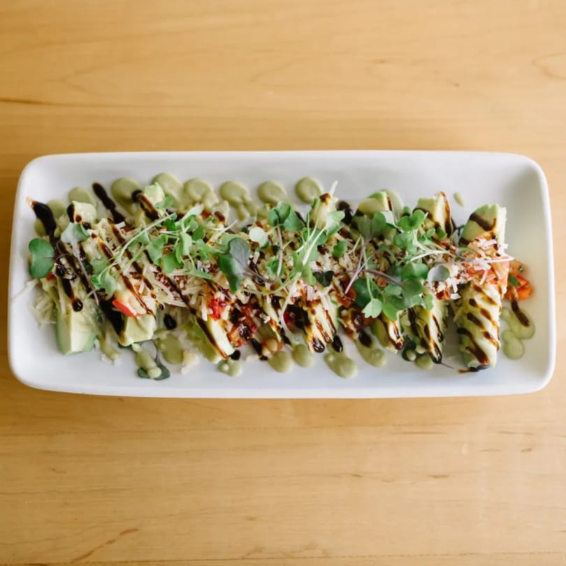 Good Kitchen's healthy avocado rolls with balsamic glaze, green sauce, and microgreens on a white plate.